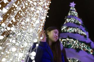 2018年12月22日,北京一名女士在聖誕樹旁自拍。