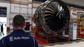 Rolls-Royce worker stands in front of a jet engine