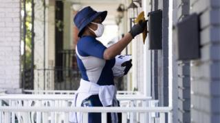 A mail carrier of the United States Postal Service delivers mail in Washington, DC, USA, 18 August 2020