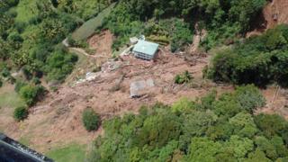 A house between uprooted trees and a precipice