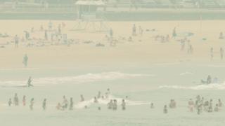 Beachgoers on Bondi Beach amid a heavy smoke haze,