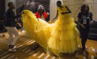 Fashion designers, stylists and assistants help a model with her dress backstage at Dakar Fashion Week in Dakar, Senegal