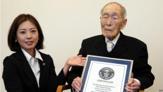 In this file picture taken on 20 August 2014, one-hundred-eleven-year-old Japanese man Sakari Momoi (R) receives a certificate naming him as the world's oldest man by the Guinness World Records at a hospital in Tokyo