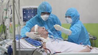 Стивен Кэмерон с размытым лицом кормит персонал в масках на больничной койке