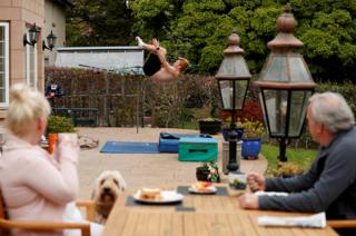 A diver practises at home in the garden as his parents look on