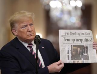 President Donald Trump holds a copy of the Washington Post