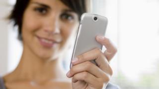 mujer mostrando a la cámara el celular