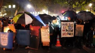 A shield line, made up of protesters with umbrellas and trash cans, advances on federal officers during a protest in front of the courthouse, 21 July 2020