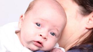 Baby being held by his mother, part of a couple from Ireland who travelled to Ukraine for surrogacy