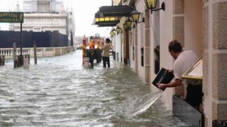 A man emptying a bucket of water in Venice on October 29, 2018