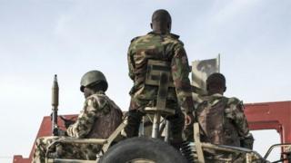 Nigerian soldiers with weapon on top vehicle