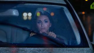 Mujer conduciendo de noche con cara de miedo.
