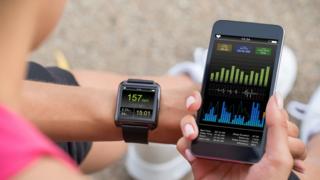Mujer observa su pulsera inteligente y aplicación de pulso cardíaco en su teléfono