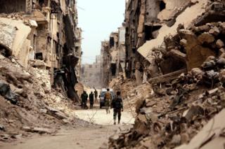 Soldiers walk past damaged buildings in Yarmouk Palestinian camp in Damascus, Syria May 22, 2018