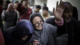 A distressed woman mourns surrounded by other people inside a building in Khan Younis