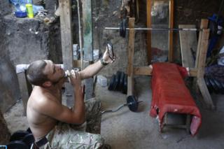 Украинский военный бреется, глядя на свое отражение в мобильном телефоне. Линия фронта вблизи Маруиполя, 12 июня 2018 года
