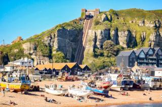 A beach with a cliff railway in the background