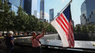 A man flies a US flag at the 9/11 memorial in NYC
