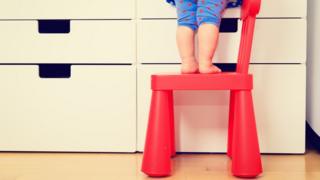 Niño de alrededor de dos años subido a una silla