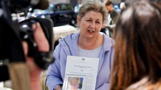 The widow of a former subpostmaster holds his photograph as she speaks to members of the media outside the Royal Courts of Justice in London, on April 23, 2021, following a court ruling clearing subpostmasters of convictions for theft and false accounting