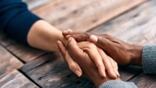 Cropped shot of two unrecognizable people holding hands, comforting each other