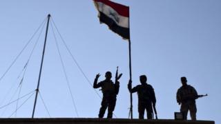 Iraqi soldiers raise the national flag over a government building in Ramadi. Photo: 21 December 2015