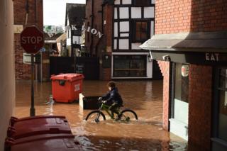 A boy cycles through flood water in Hereford.