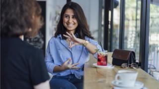 Mujer hace gesto con la mano