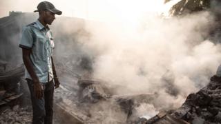 A man stand in front of a burnt down house in the PK5 district in Bangui on December 26, 2019, after clashes erupted when traders took up arms to oppose taxes levied by militia groups.