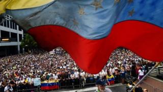 A Venezuelan national flag flutters during a mass opposition rally against President Nicolas Maduro in which Venezuela"s National Assembly head Juan Guaido (out of frame) declared himself the country"s "acting president", on the anniversary of a 1958 uprising that overthrew a military dictatorship