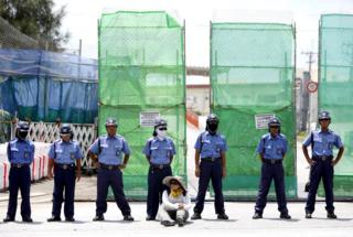 Woman sat on the ground in front of a line of police