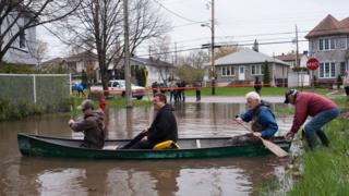 Residents in a canoe paddle on the flooded streets in Pierrefonds on Sunday May 7, 2017.