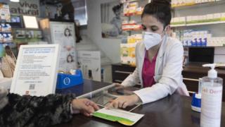 A pharmacist shows an antigen test to a person at Las Gemelas pharmacy on 10 January 2022 in Madrid Spain