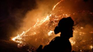Firefighters stand watch by a fire line along Mayacama Club Drive as the Kincade Fire burns on the outskirts of Santa Rosa