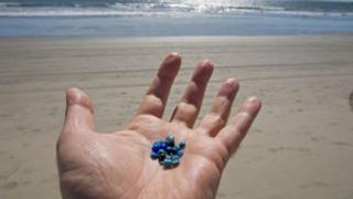 Nurdles en la mano de un hombre.