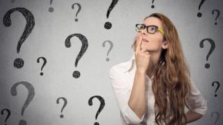 Mujer mirando a signos de interrogación.