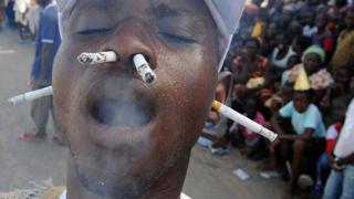 Un homme fume la cigarette avec le nez et les oreilles lors du carnaval annuel des Popo à Bonoua.