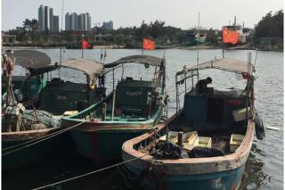 Рыбацкие лодки с красными флагами в гавани в Баймажинге, провинция Хайнань, 7 апреля 2016 г.