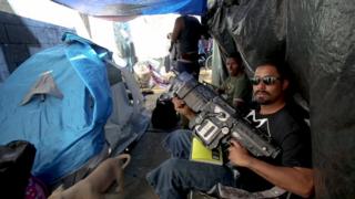 Homem usando arma de brinquedo dentro da barraca