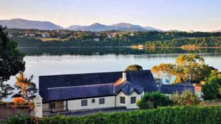 Warm sunshine glow over Menai Strait looking over roof tops and the mountains beyond