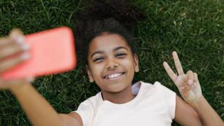 молодая девушка делает селфи на смартфоне
