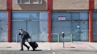 man walks past closed stores in US