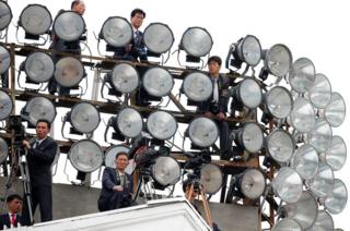 Cameramen take up position on a building in Pyongyang, North Korea, during a mass rally and parade