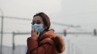 A woman wearing a face mask makes her way along a street in Beijing