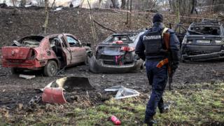 A police officer inspects destroyed cars in Lviv