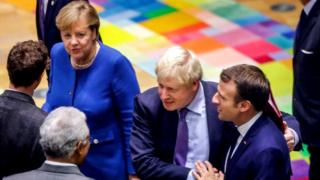 British Prime Minister Boris Johnson (2nd R) salutes French President Emmanuel Macron (R) upon their arrival for a round table meeting as part of a European Union summit at European Union Headquarters in Brussels on October 17, 2019