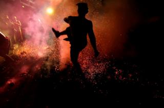 A Balinese man kicks burning coconut shell