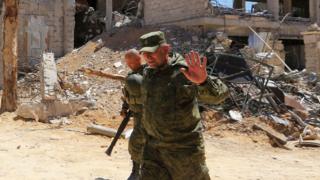 Russian forces walk past damaged buildings in Douma on the outskirts of Damascus on April 16, 2018