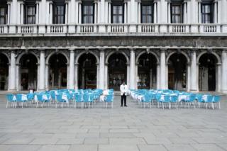 in_pictures A waiter stands by empty tables outside a restaurant