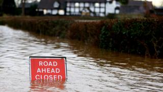 A sign is partially submerged as the village of Severn Stoke is cut off amid flooding